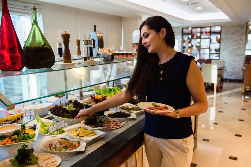 Grand Mercure Majlis Residences Abu Zabi Zewnętrze zdjęcie A woman selecting food from a buffet
